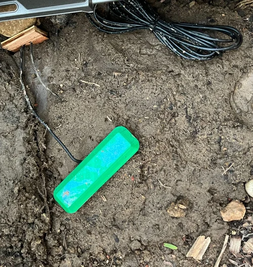 A Terracell sensor buried in soil next to its wiring